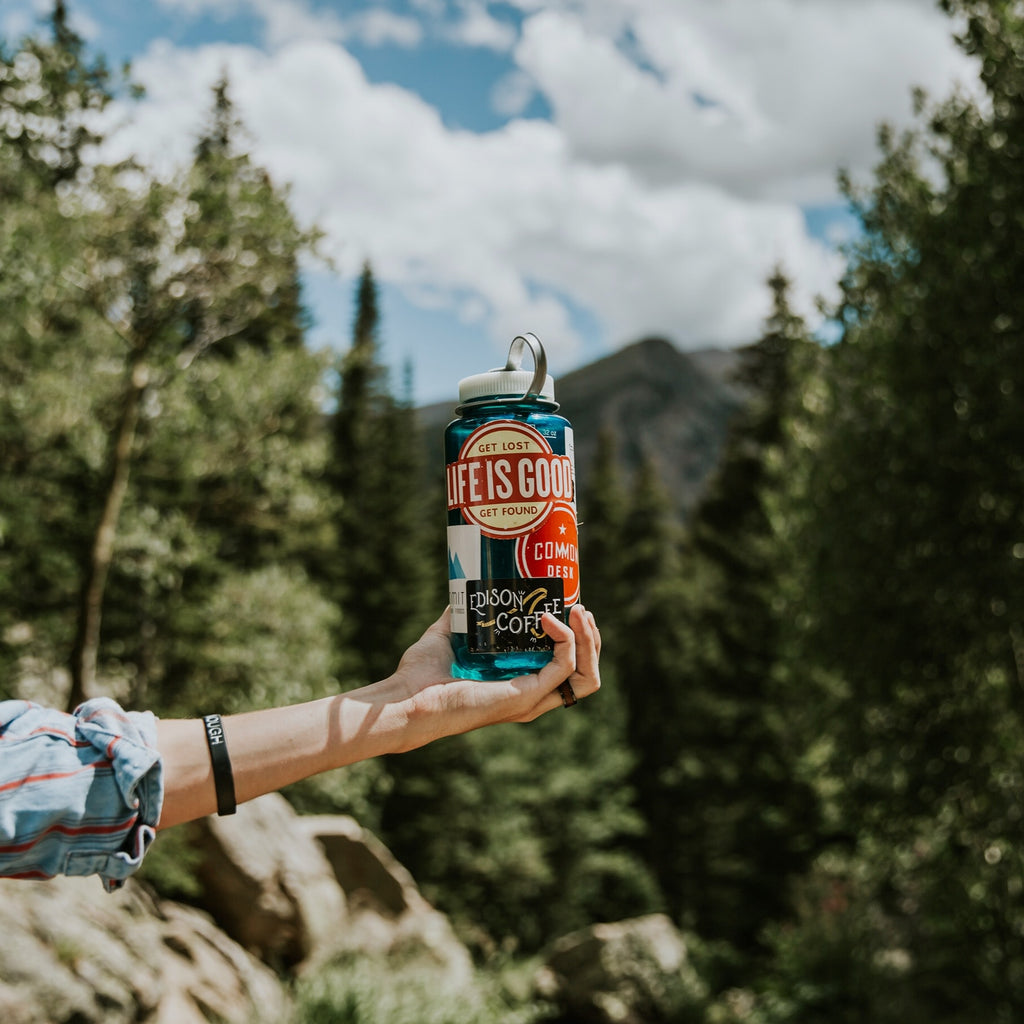 hand holding water bottle with camping stickers