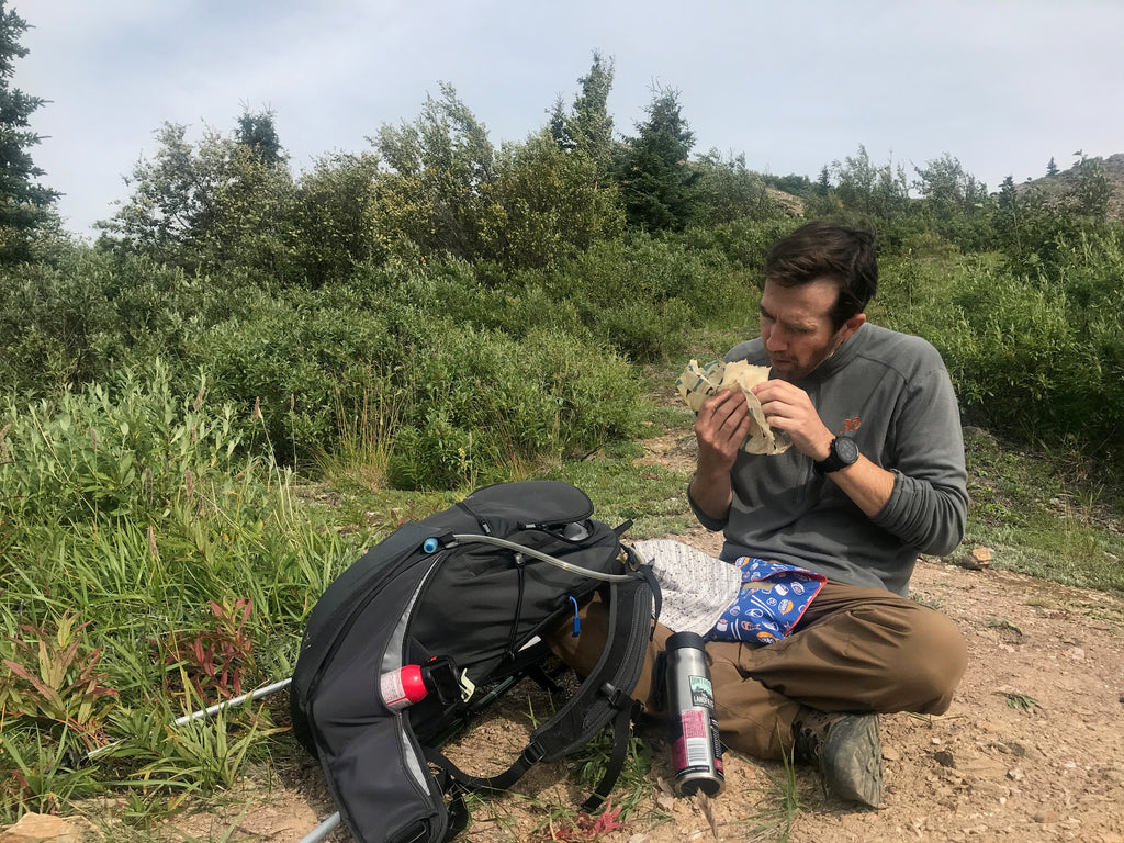 Man eating while hiking on a trail