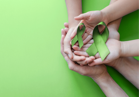 hands holding green ribbon for mental health awareness month