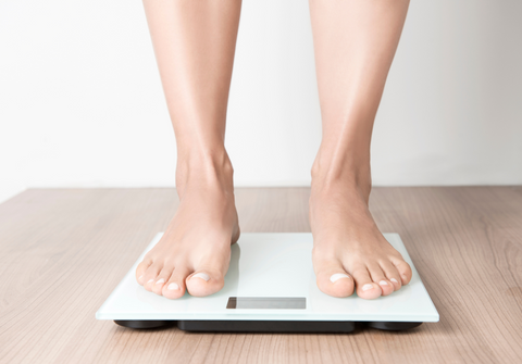 feet on scale measuring how sleep can affect weight loss