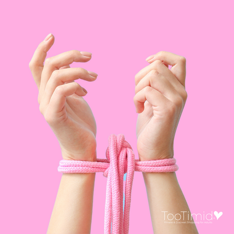 Hands with pink shibari rope wrapped around wrists