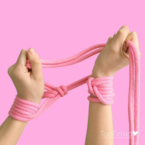 Another set of hands with shibari rope wrapped around wrists and in hand