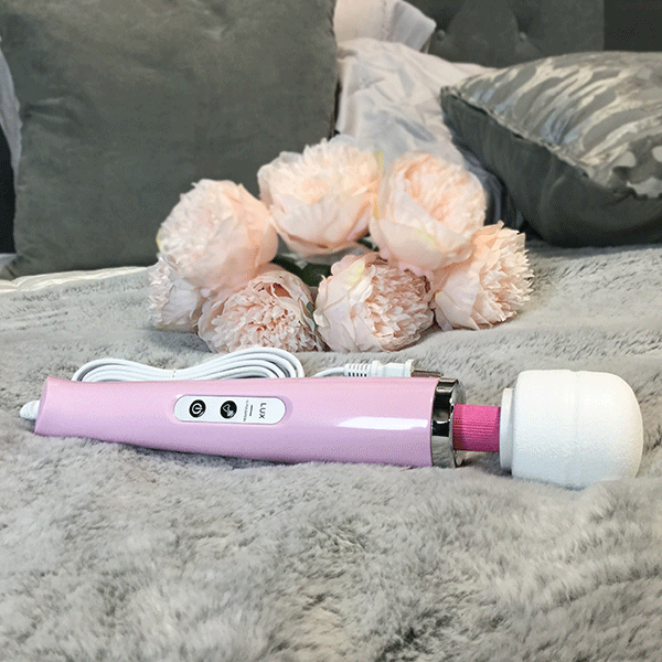 Pink Lux Massage Wand On Bed Next To Bouquet Of Pink Flowers