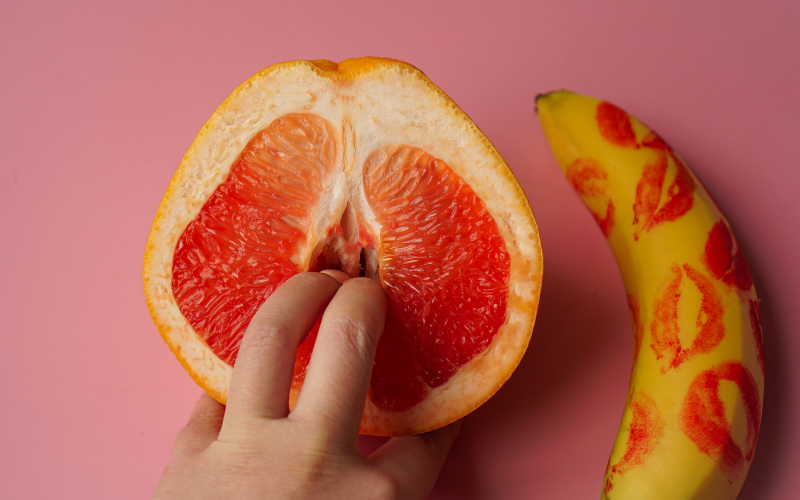 Image of fingers entering a cut open grapefruit