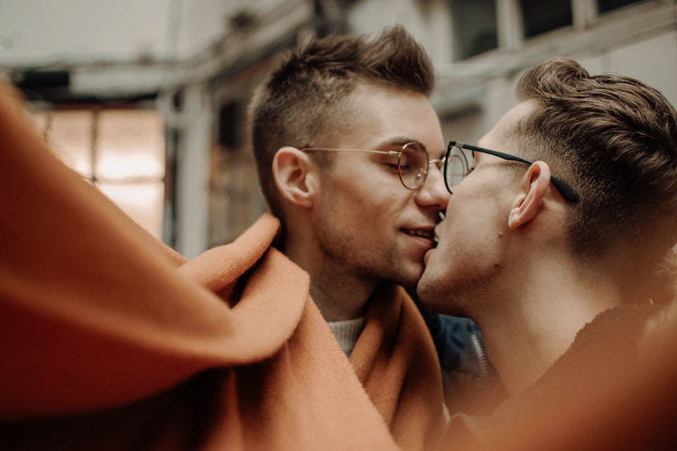 Two men with glasses leaning in for a kiss.