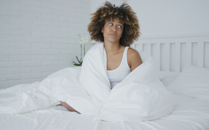 Image of woman sitting in bed looking annoyed