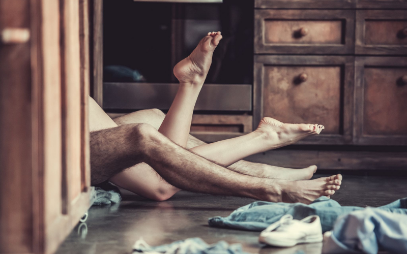 Woman and man's legs entangled on the floor of the kitchen