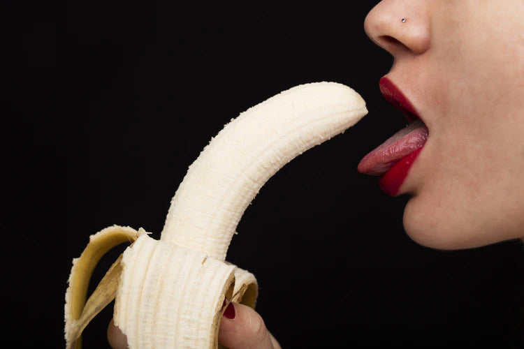 a woman opening her mouth to eat a banana