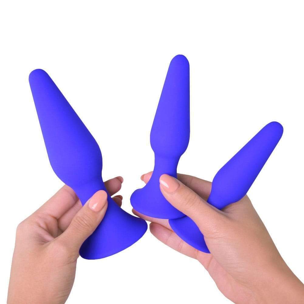 Hands holding blue anal training set of 3 butt plugs with suction cup bottoms