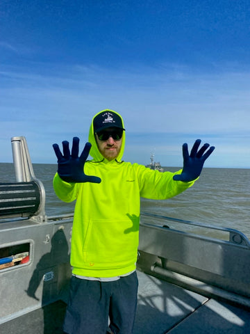 Christian wearing a day glow sweatshirt and blue glove liners while on the boat.