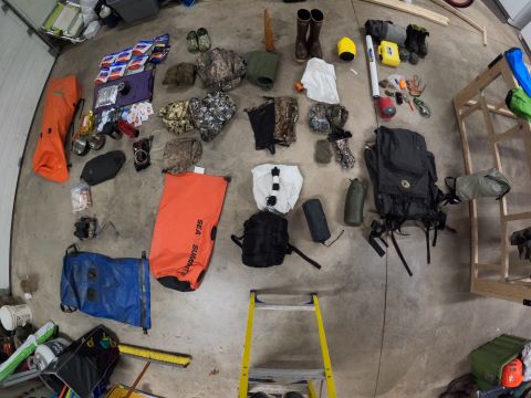 Steve and Sam have all of their gear laid out in a bay. It is a downward shot where the gear takes up the whole concrete floor.