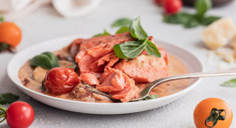 Side profile view of the cooked salmon in a bowl with the creamy sauce surrounding it