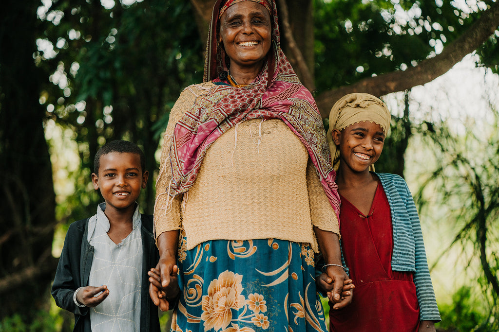Ababech stands as a proud mom with her two daughters outside her home in Ethiopia.