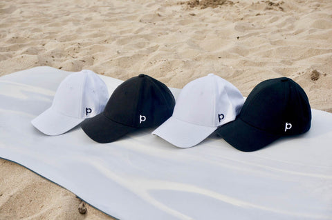 4 hats on a beach towel white and black baseball caps for women ponytail