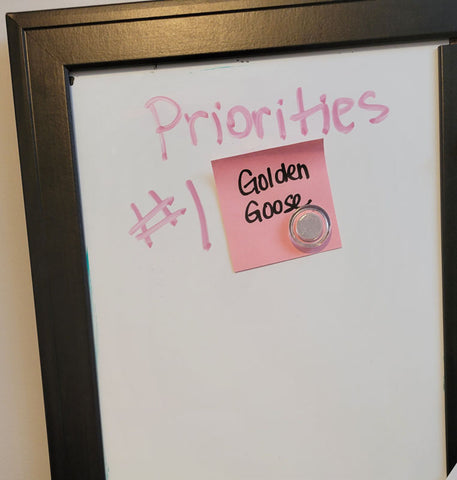 White board with words written on it that say priorities number 1 golden goose