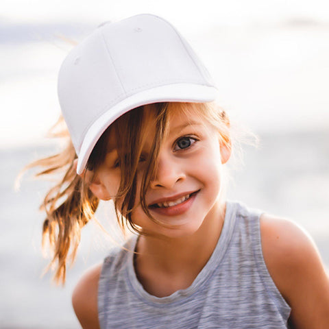 Little girl wearing a white Ponyback ponytail youth hat at the beach