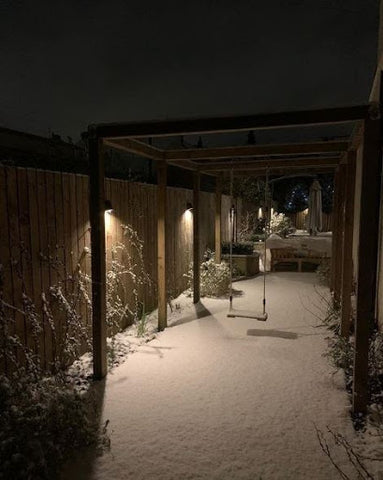 snowy garden with wall lights