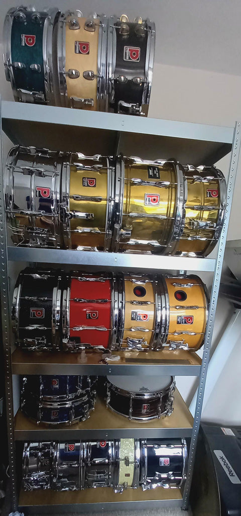 a variety of premier snare drums displayed on a rack