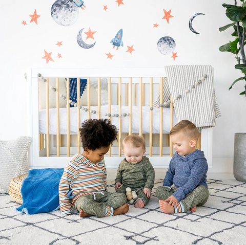 Three kids in a bedroom with spaceships wallpaper