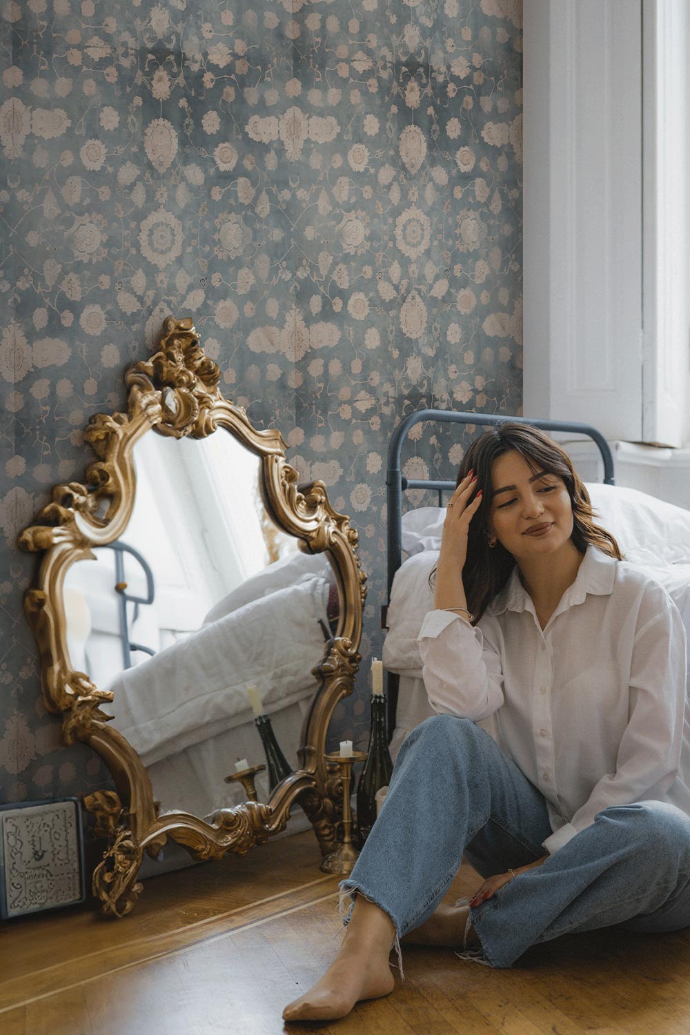 Girl sitting on floor in bedroom. Antique gold mirror on floor in front of the Blue Medallion Wallpaper.