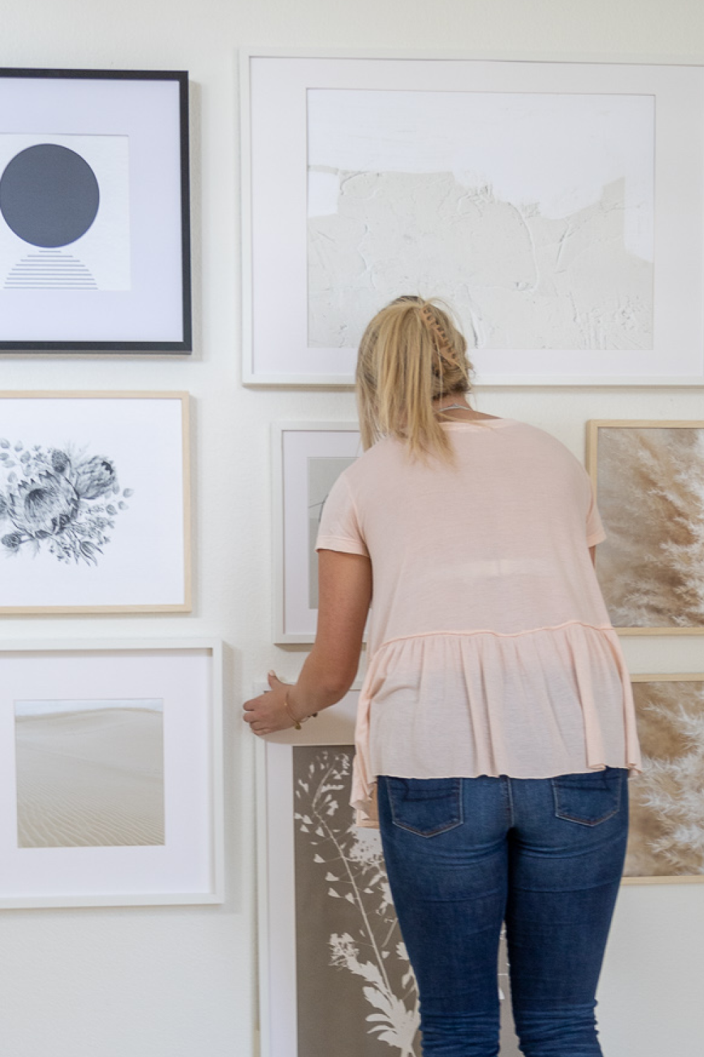 woman hanging pictures for wall gallery