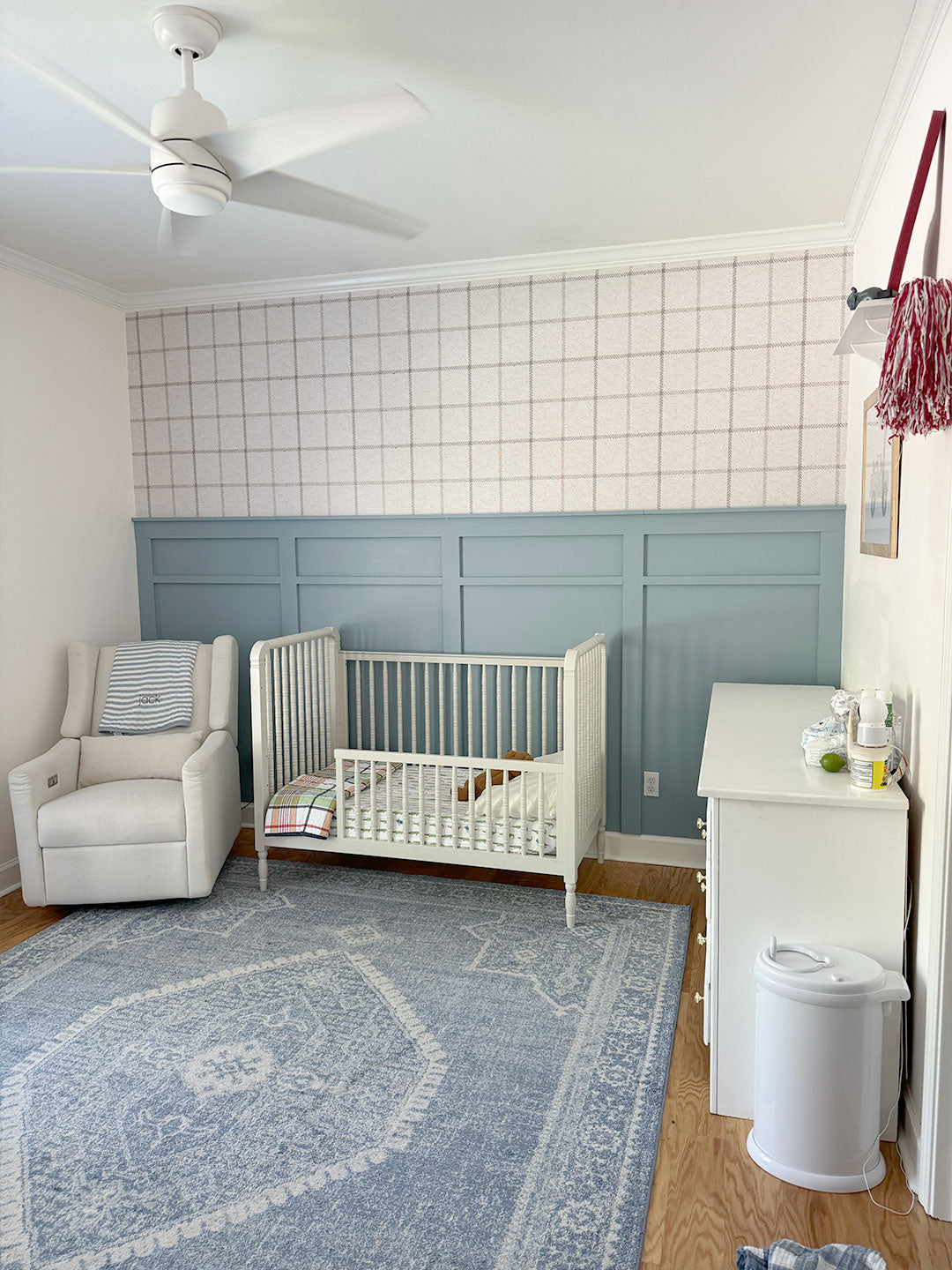 A nursery for a boy showcasing plaid wallpaper and blue accents, creating a welcoming and thematic space.