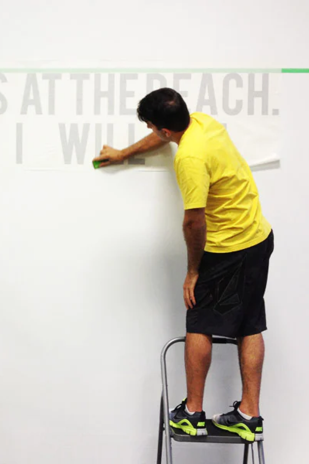 man installing wall decals at gym