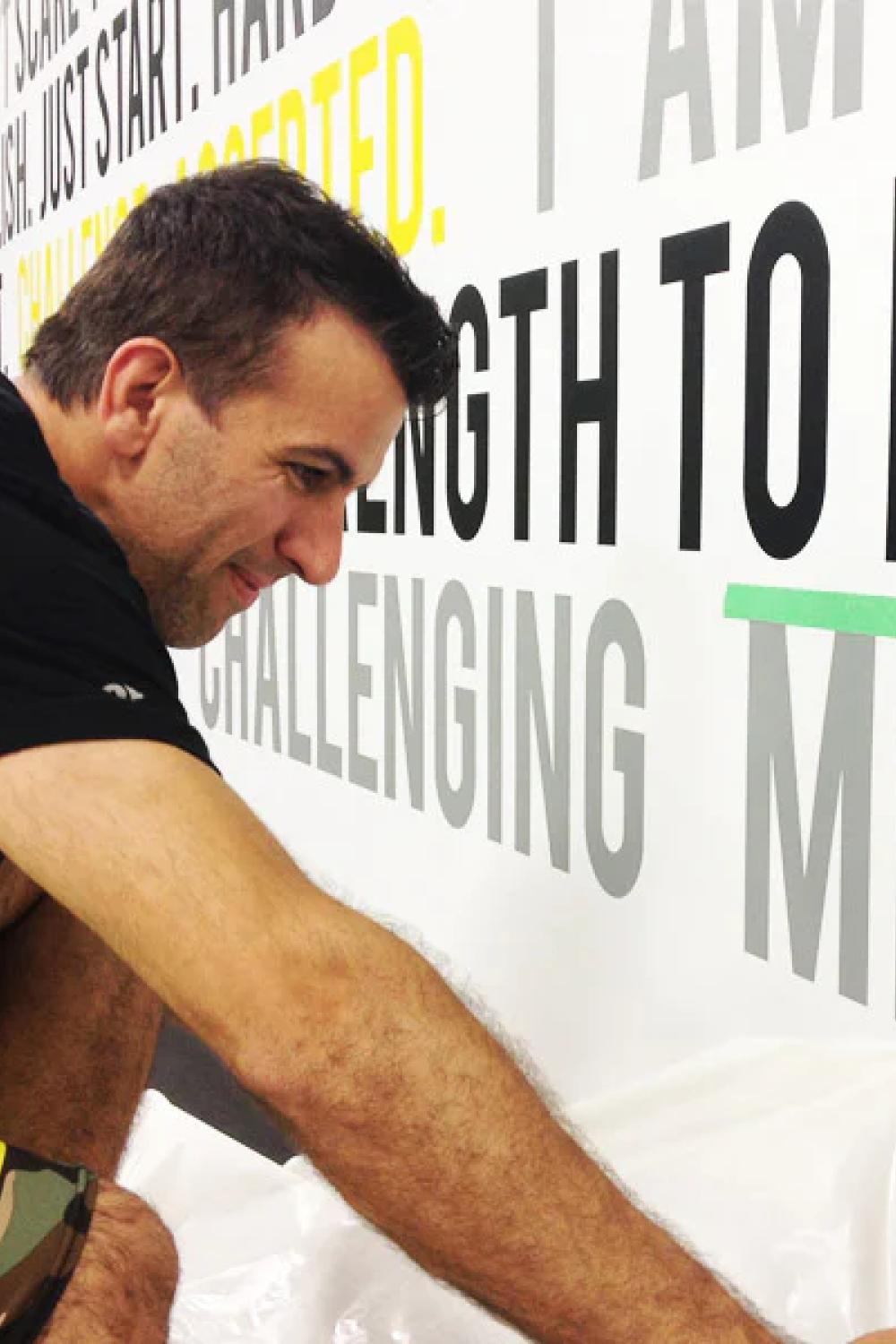 man installing wall decals in gym