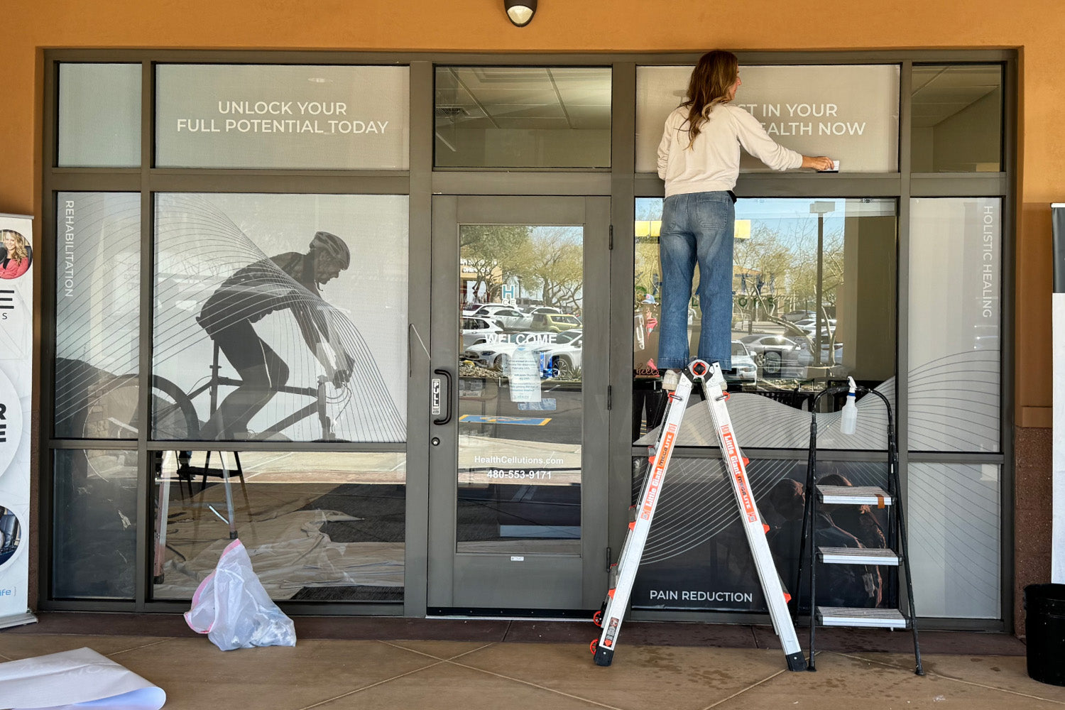 woman installing storefront display from urbanwalls