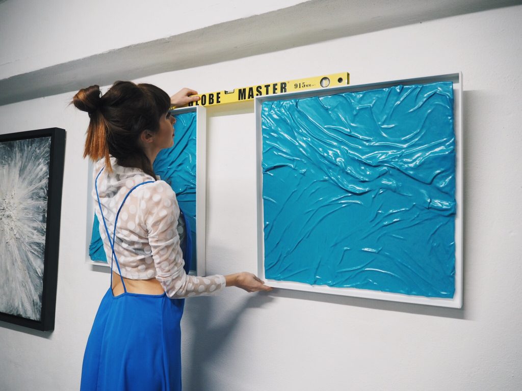 Lauren Baker using a spirit level to hang artwork on a wall