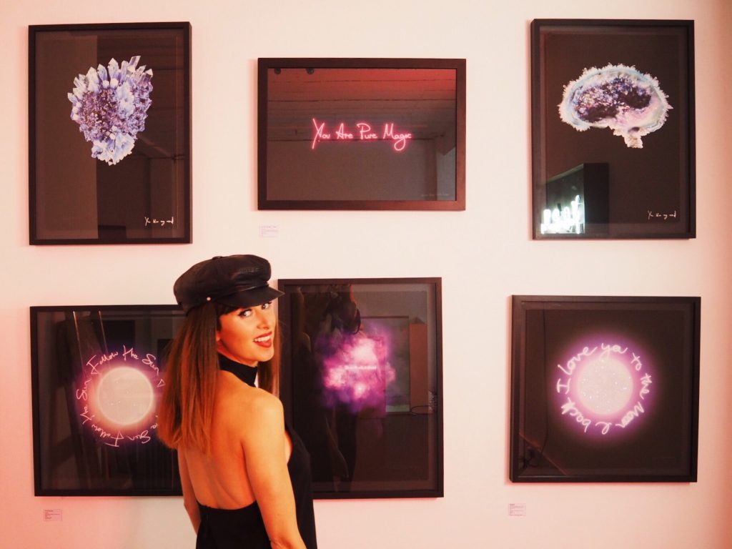 Lauren Baker beside 6 pieces of artwork on wall