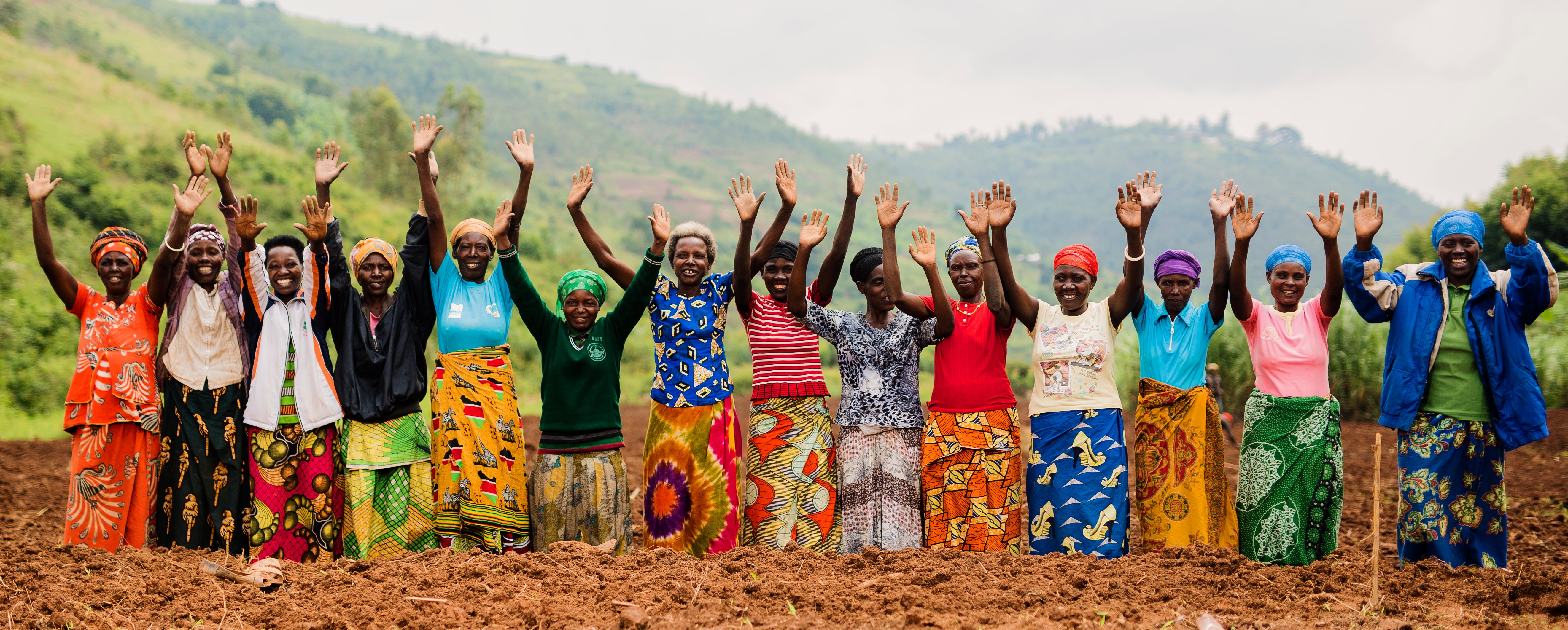 14 women kneeling down in a row with their hands in the air