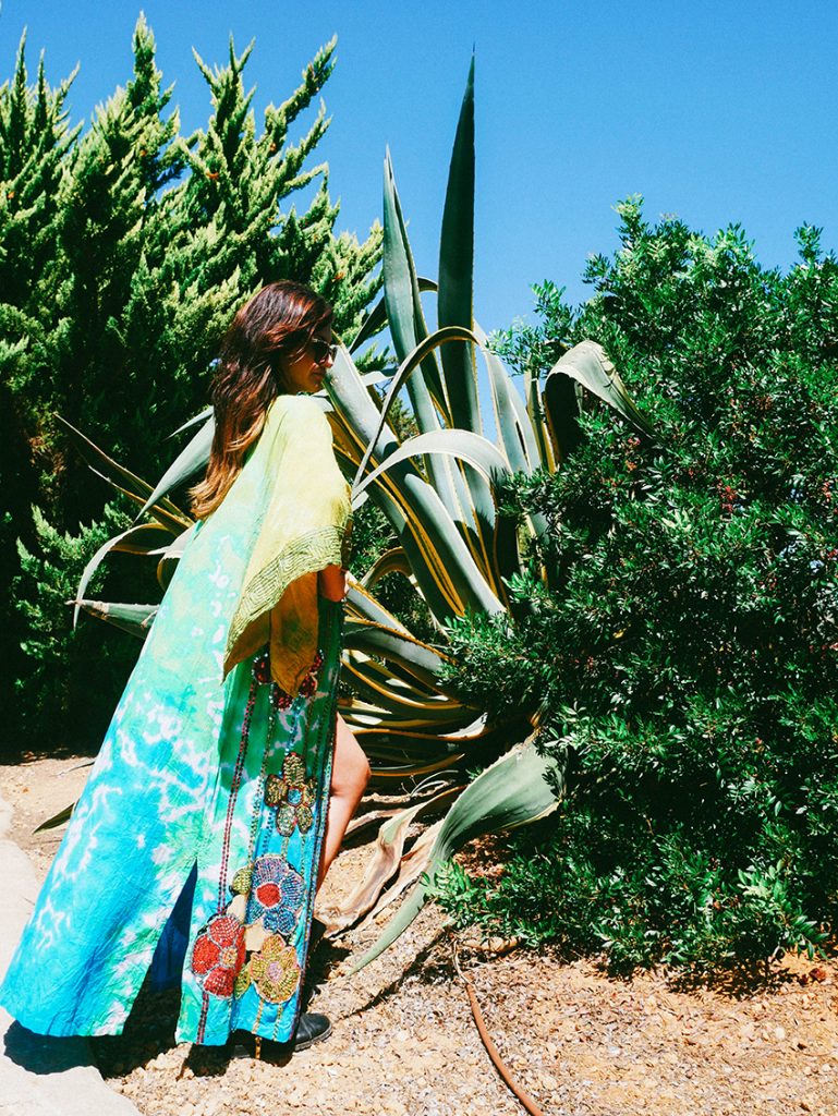 Kate Marron wearing a long colourful gown stood next to shrubbery