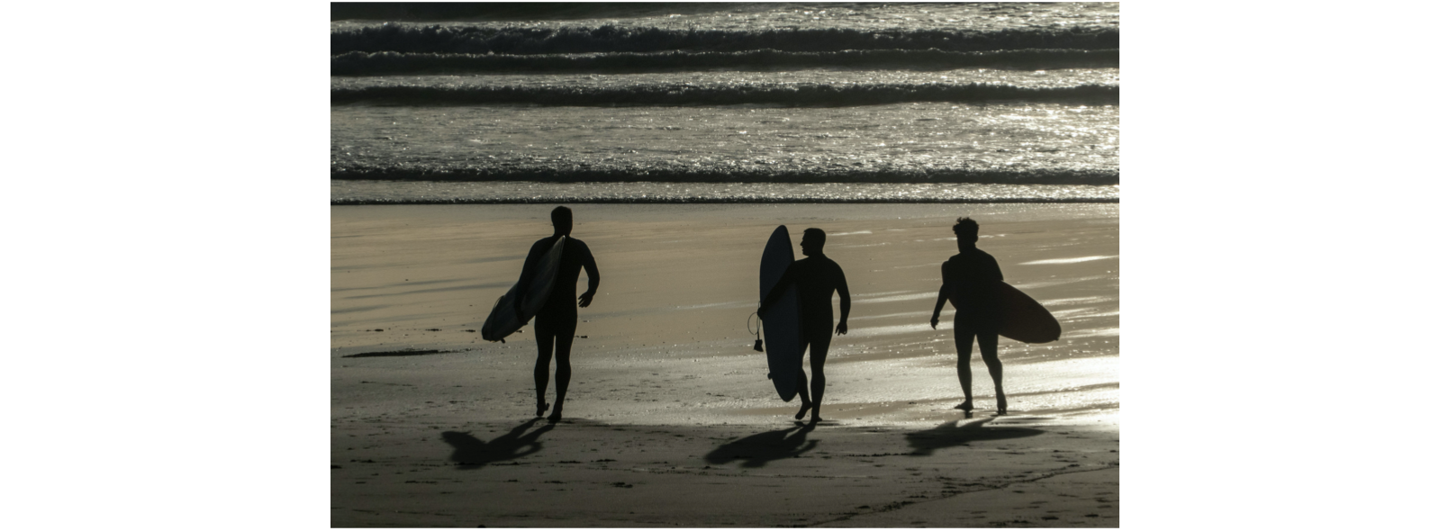 3 surfers on a beach