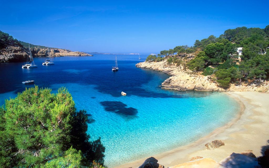 Cala Salada beach, in Ibiza, with boats on the water