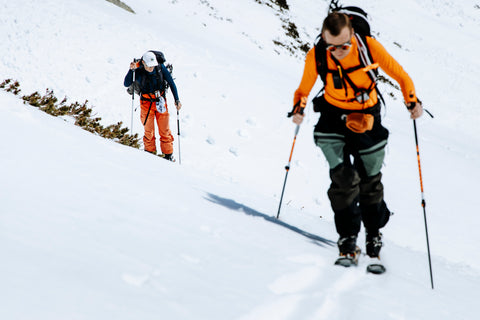 Two men climbing up a snowy mountain wearing Brubeck Active Wool base layers