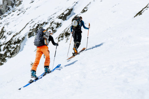 Men wearing Brubeck base layers climbing a snowy mountain with skiis