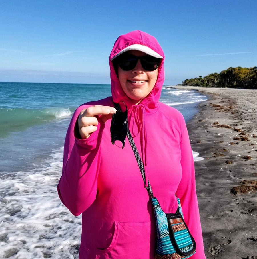 Sara on a beach walk, holding a washed up shark egg case.
