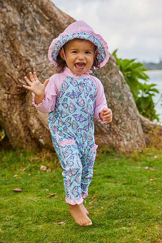 Baby girl laughing at the beach in UV swimwear