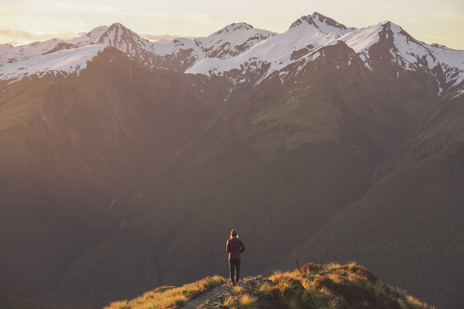 personne debout devant les montagnes au coucher du soleil