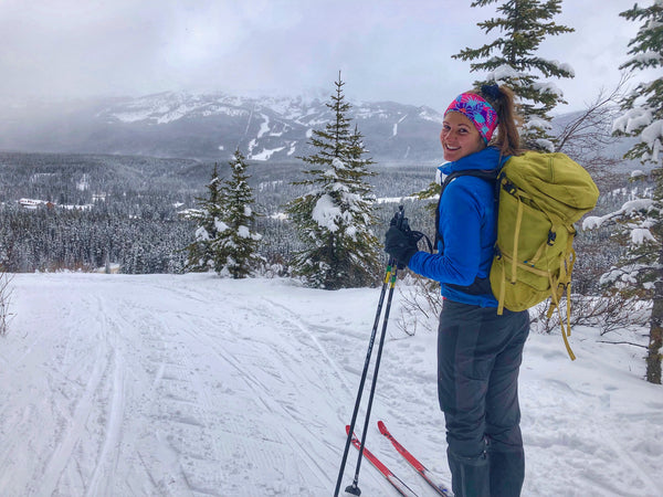 Fille avec sac à dos Ski à travers des montagnes enneigées