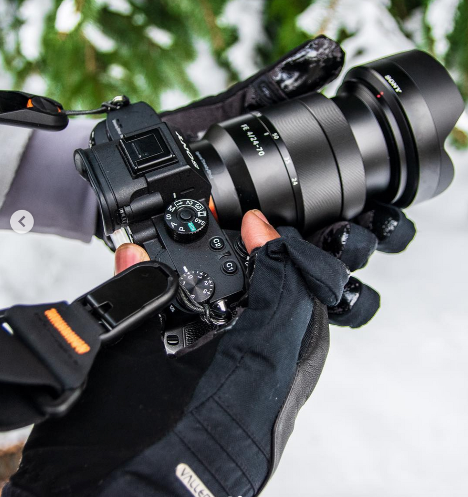 Guanti fotografici che tengono una macchina fotografica nella neve