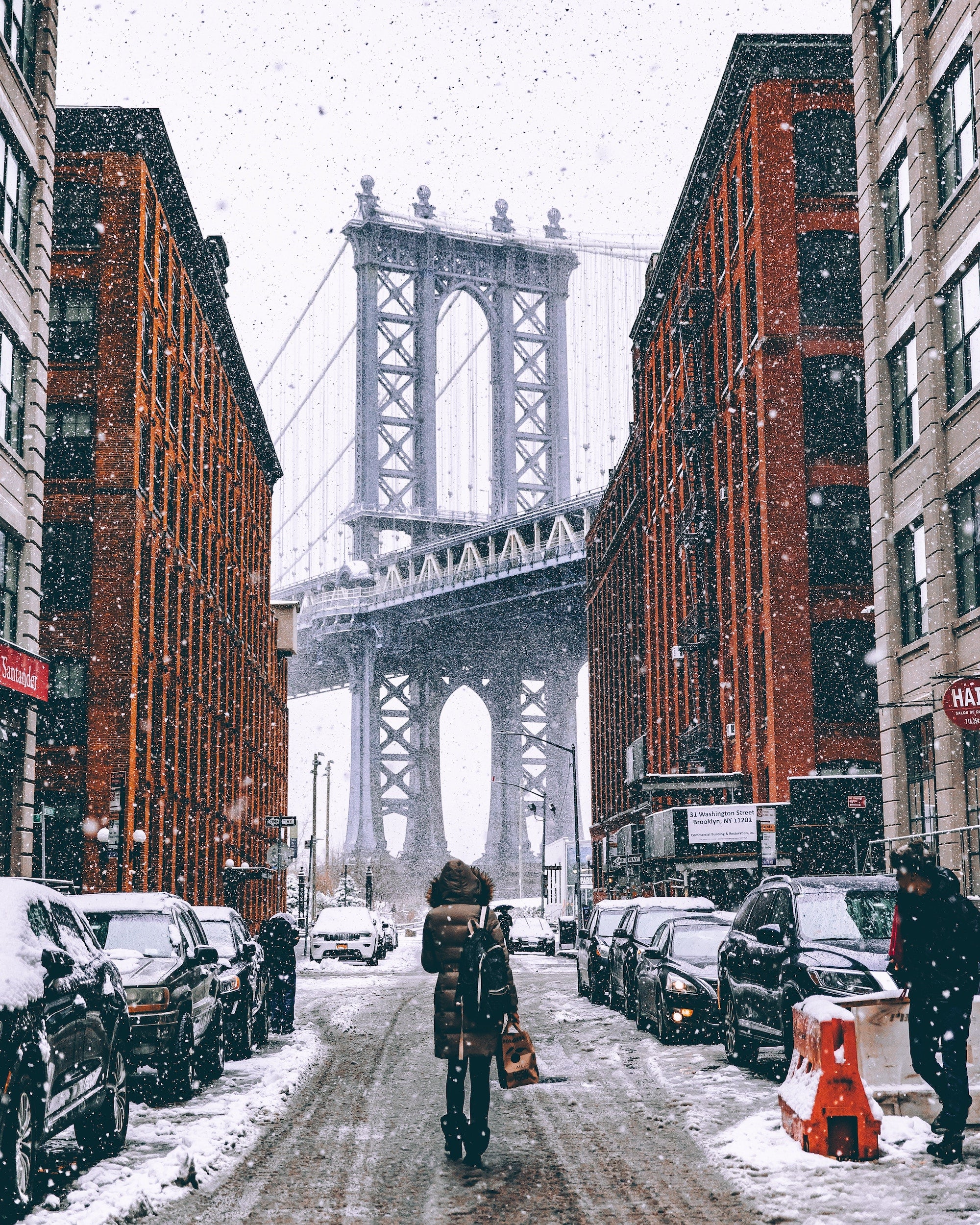woman standing in the middle of a snowy street with bridge in the background