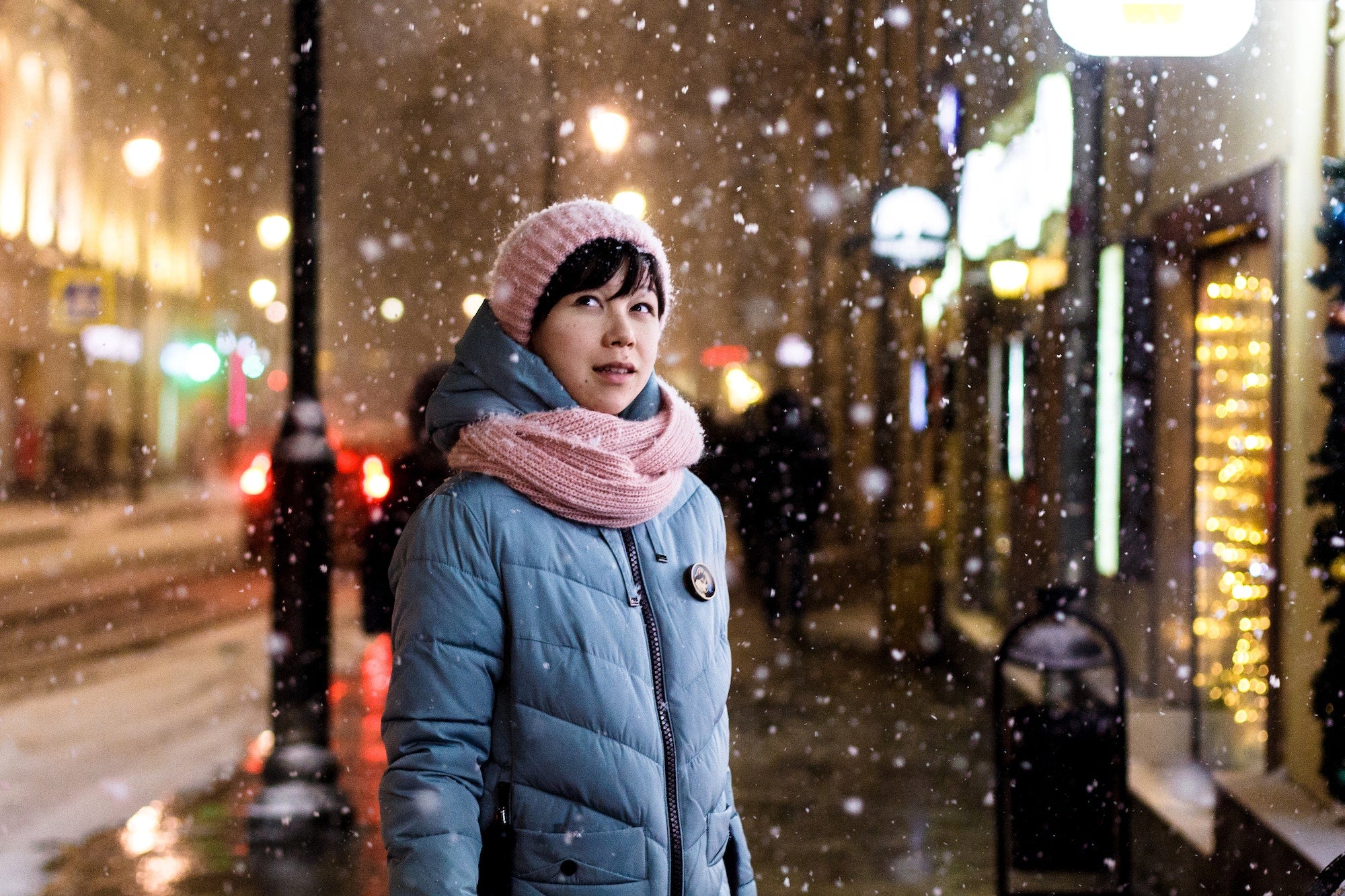 woman standing on snowy street looking off into the distance