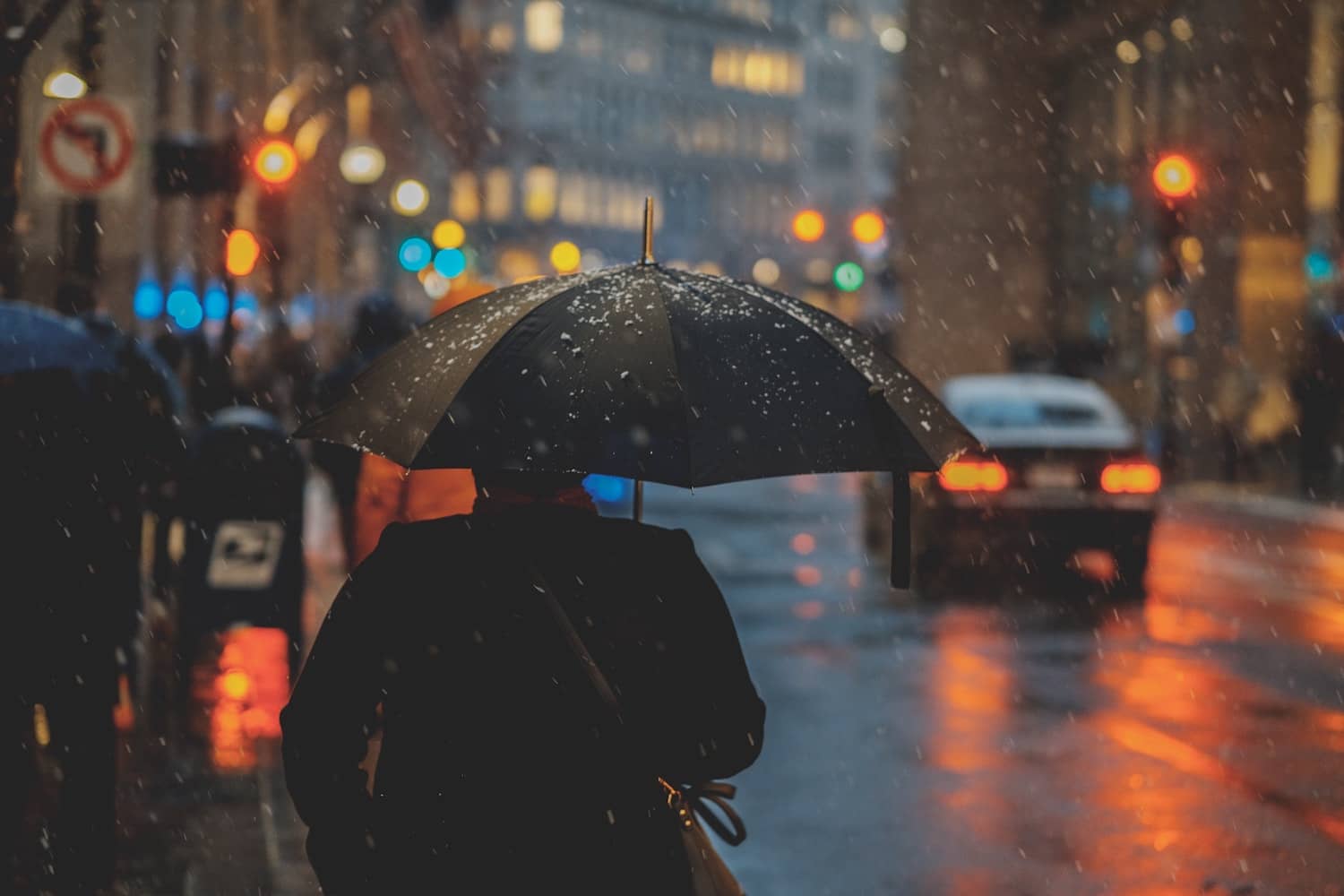 person under umbrella standing in the rain 