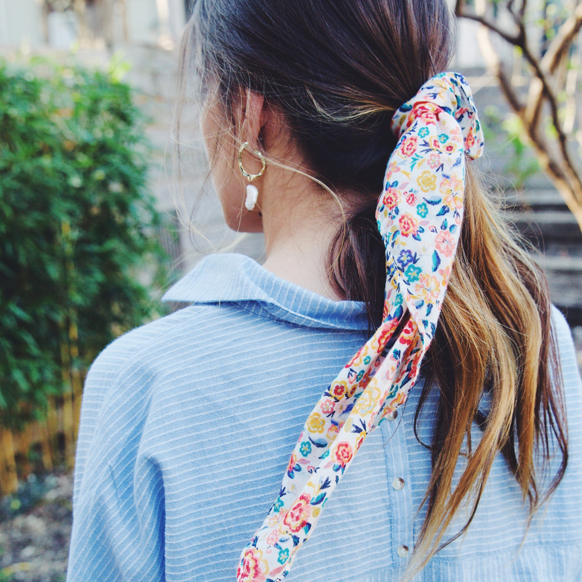 girl wearing blue and white striped shirt, pearl earrings, and a colorful printed hair scarf.