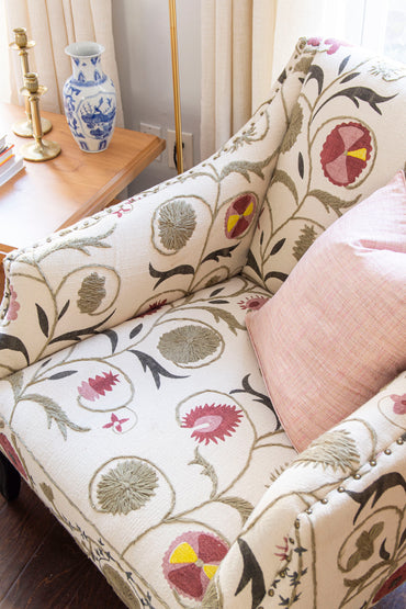 Classic living room design in Atlanta with Oka Tarma embroidered armchair, brass coffee tables, silk pillow, and floral rug on design blog The Francis Files by Kevin Francis O'Gara