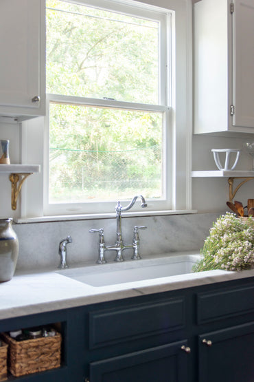 Historic kitchen renovation with navy blue cabinets, Georgia marble countertops, fireclay sink, bridge sink faucet, mixed metals, brass and nickel, and Alabaster paint by Kevin Francis Design