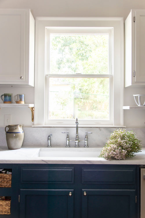 Historic kitchen renovation with navy blue cabinets, Georgia marble countertops, fireclay sink, bridge sink faucet, mixed metals, brass and nickel, and Alabaster paint by Kevin Francis Design