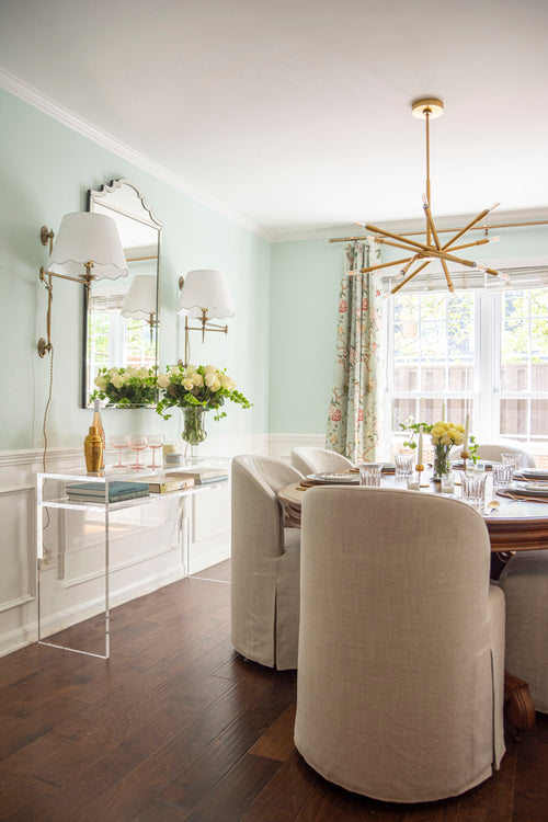 Modern classic dining room with gold chandelier, antique dining table, linen slipcover chairs, plug-in sconces, and Sherwin Williams Green Trance paint with chair rail wainscotting by Atlanta interior designer Kevin Francis O'Gara